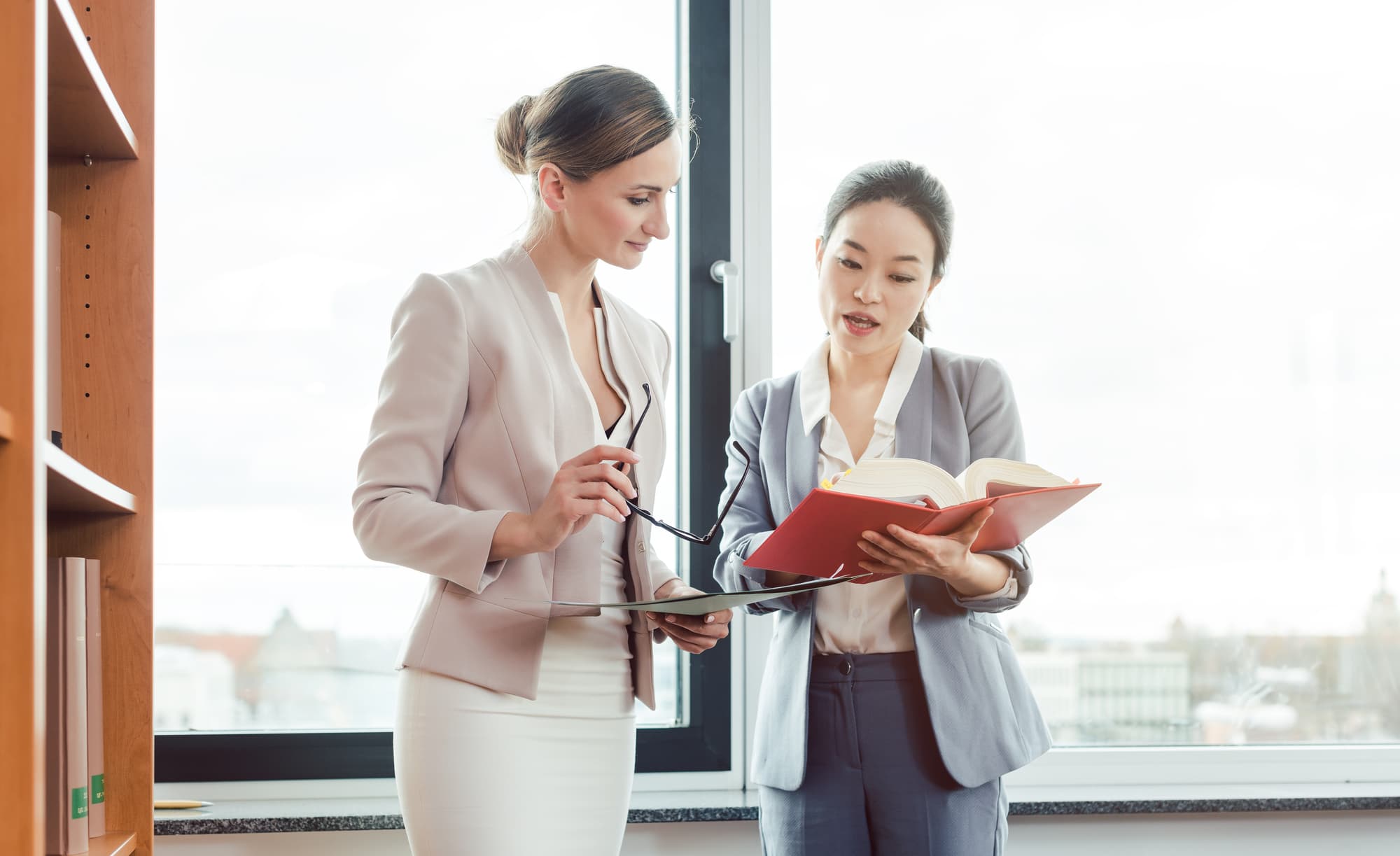 Two professional women reviewing compliance documentation